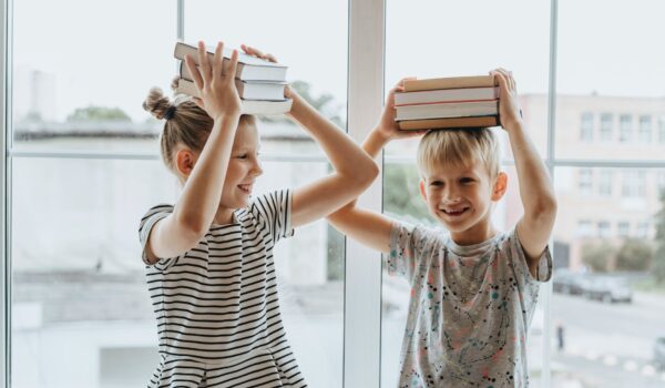 brother and sister with books on their heads